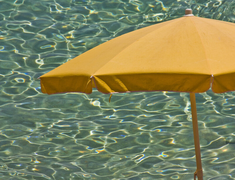 Yellow umbrella by pool water