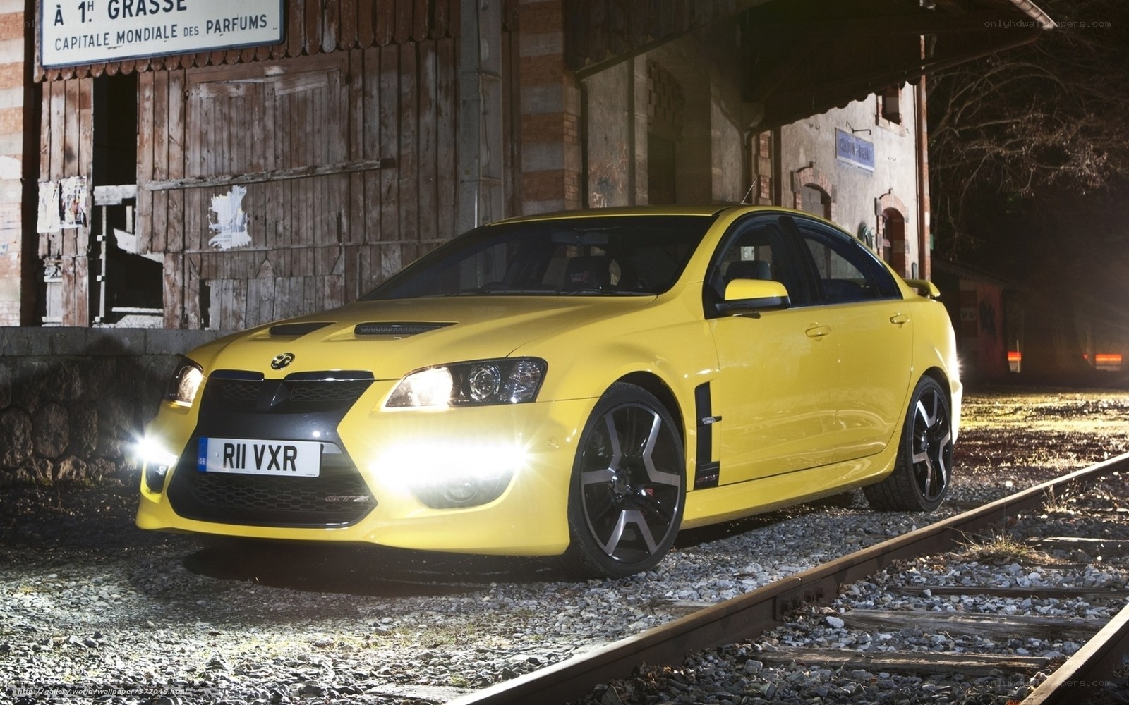 Yellow Vauxhall VXR8 on train tracks