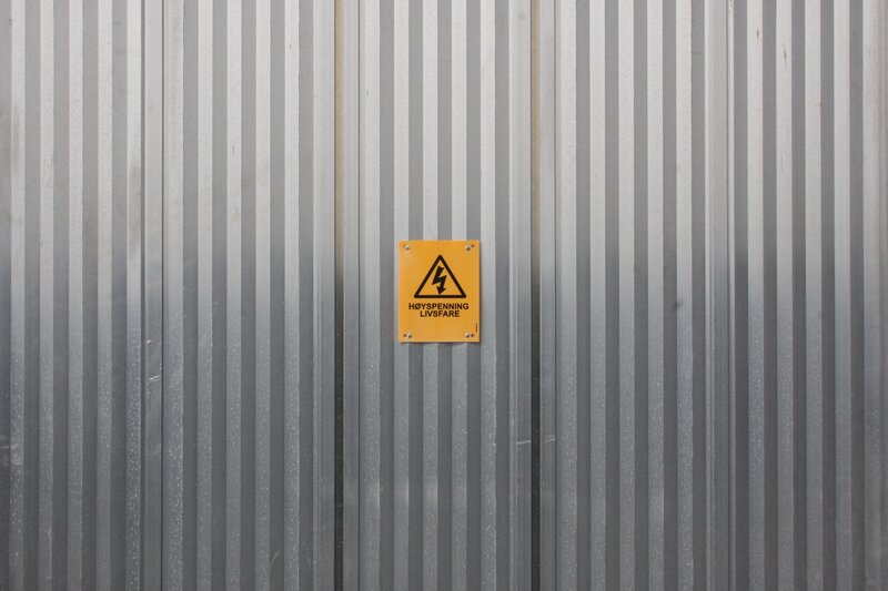 Yellow warning sign on metal wall