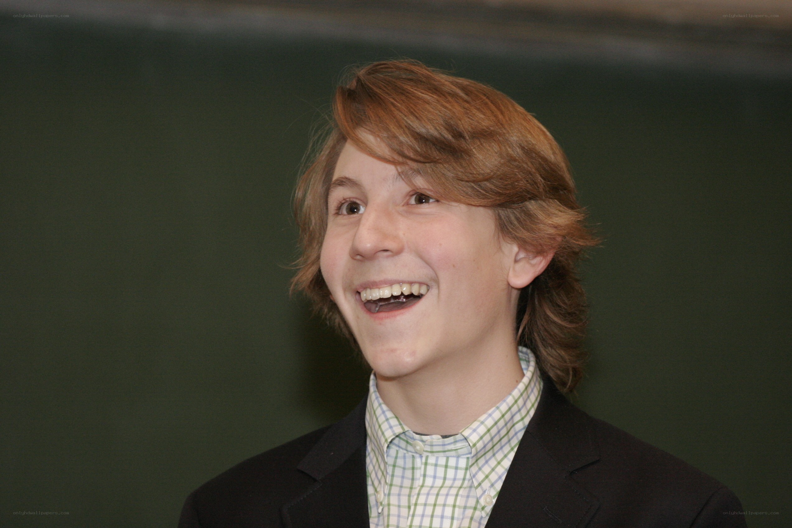 young boy laughing in suit