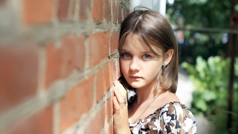 Young Girl Leaning on Brick Wall