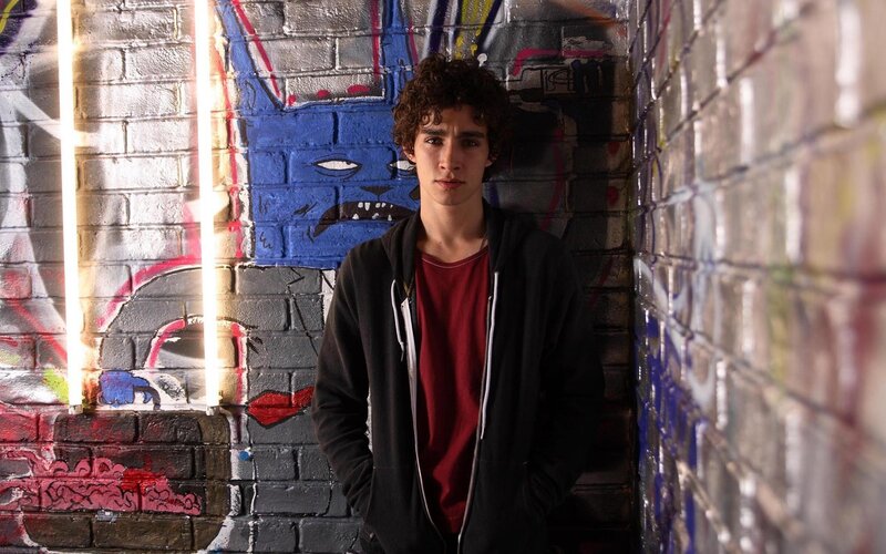 Young man in hoodie against graffiti wall