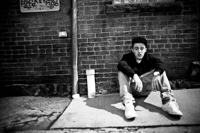 Young Man Sitting on Sidewalk