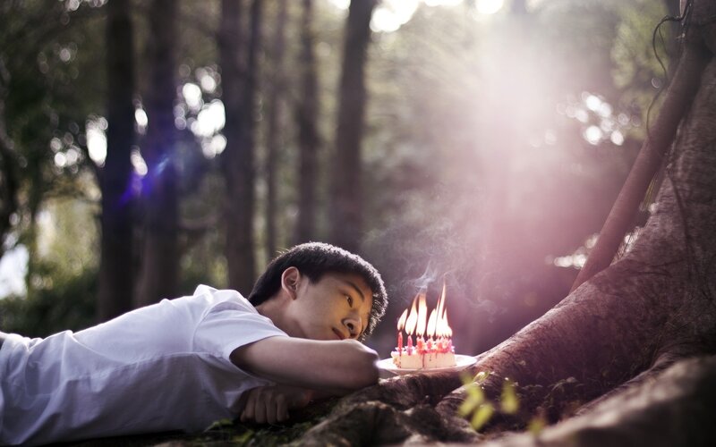 Young man with birthday cake in forest