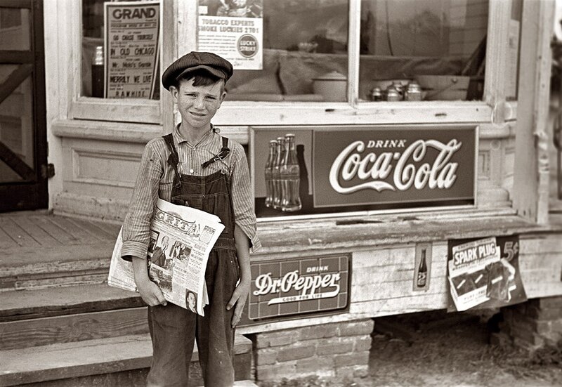 Young newsboy in front of store