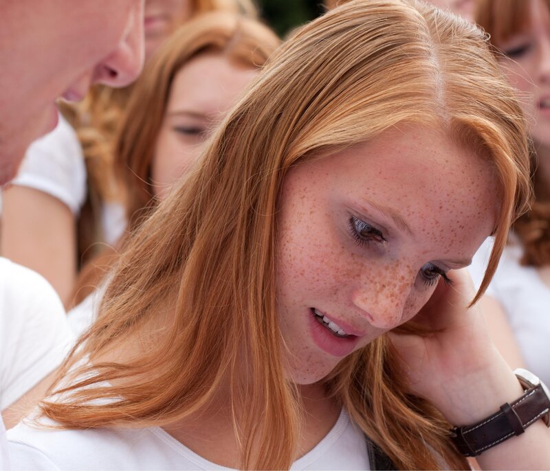 young woman with freckles looking down
